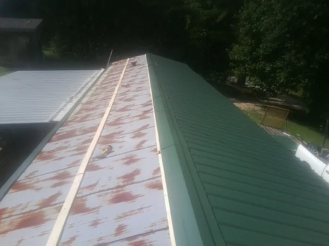 Old rusted panels beside newly installed green metal roofing — Wind Damage Roof Repair by Roofing Brothers in Sikeston