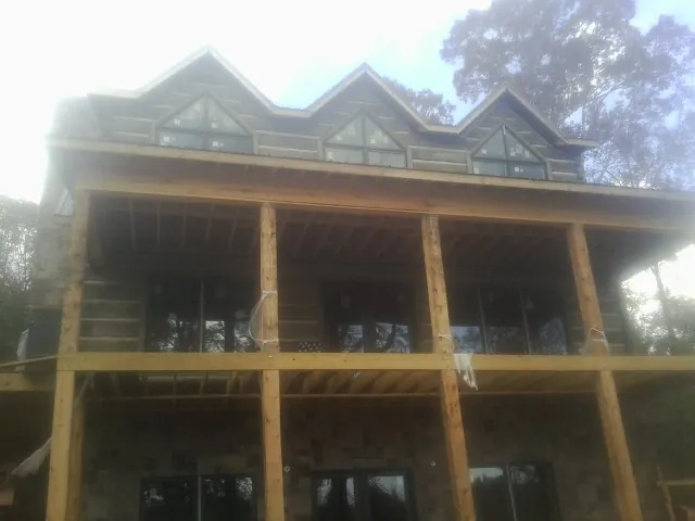 Dormers and porch framing on a large log home under construction — Roof Coating work by our crew in Sikeston