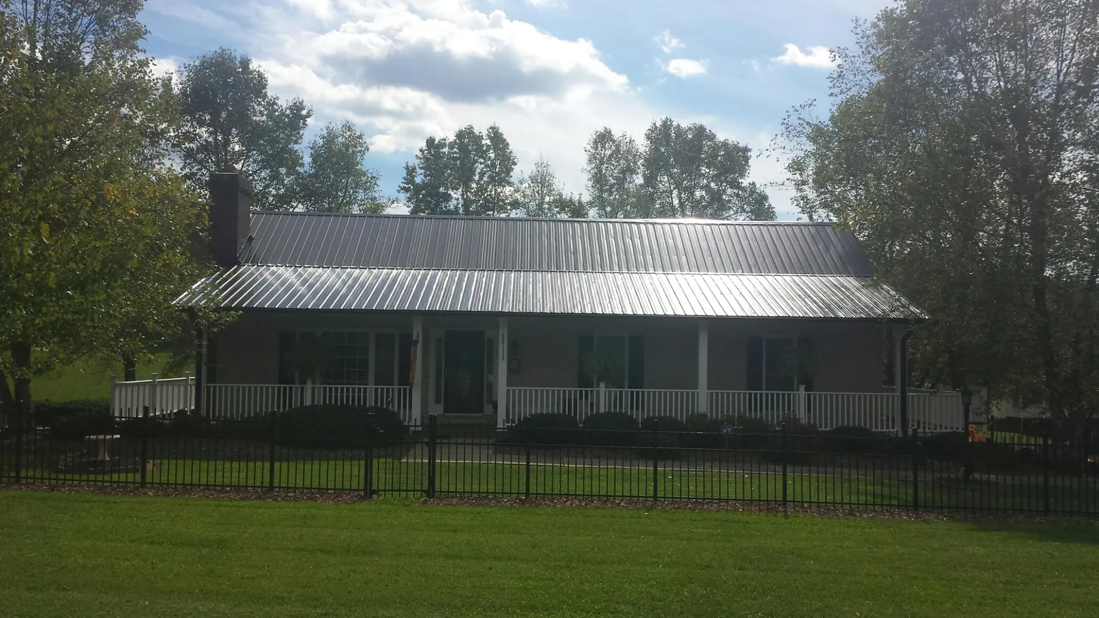 Gray metal roof on a brick ranch with a full width front porch — Gutter Guard Installation work by our crew in Sikeston