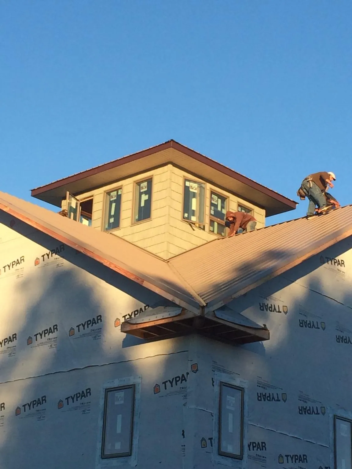 Roofers working around a rooftop cupola on a new metal roof at sunset — Roof Waterproofing in Sikeston by Roofing Brothers